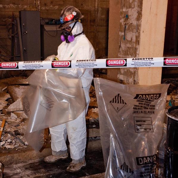 Man in a hazmat suit bagging up items in a room