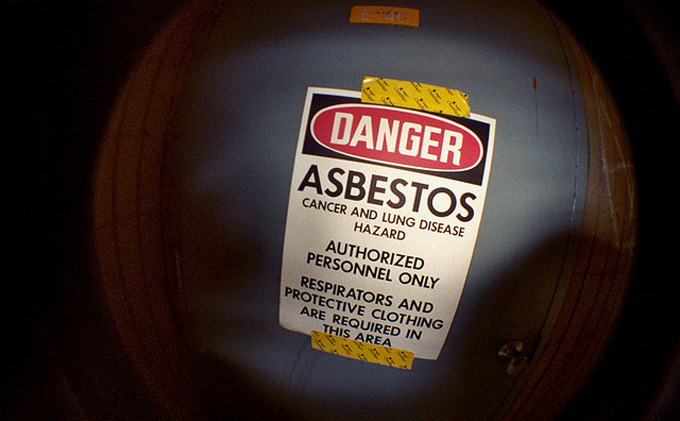 A sign reading: DANGER. ASBESTOS. Cancer and lung disease hazard. Authorized personnel only. Respirators and protective clothing are required in this area.